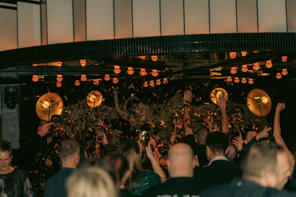 Guests dancing under a shower of gold confetti in front of the stage